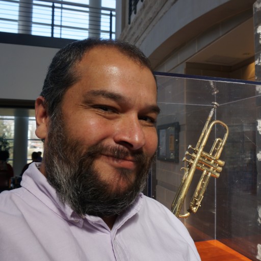 A smiling Mexican-American hombre standing beside a trumpet once belonging to Miles Davis.
